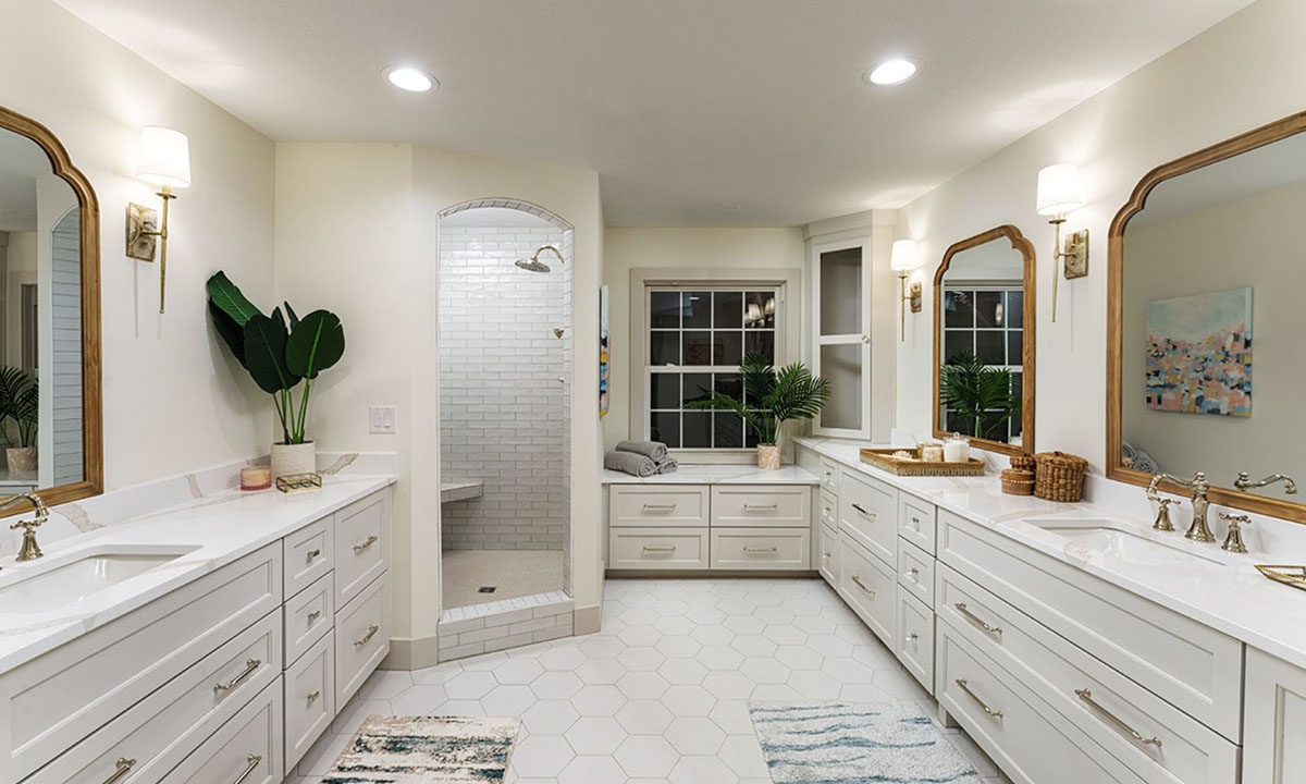 Renovated bathroom with marble look white quartz countertops, white hexagon floor tile, white subway shower tile, and white penny round mosaic shower floor tile.