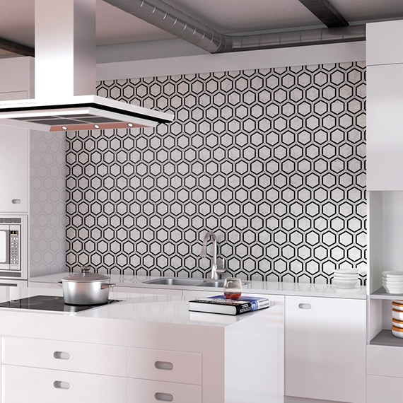 Modern kitchen with black & white hexagon backsplash, white countertop, white cabinets, island with glass stove top & hood vent.