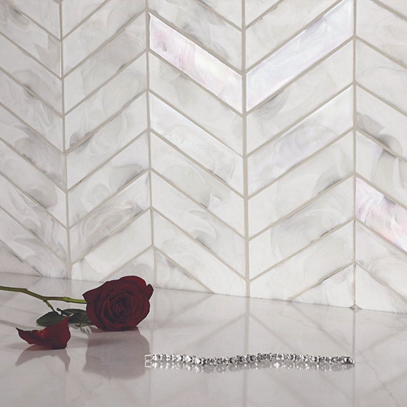 Closeup of textured wall with silver chevron mosaic tile, red rose, and diamond bracelet.