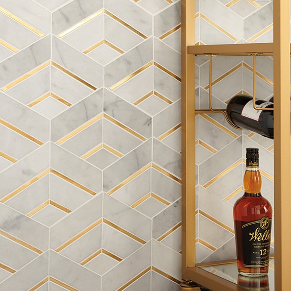 Closeup of gray marble and antique brass mosaic wall tile and brass beverage cart with a bottle of whiskey and a bottle of wine.